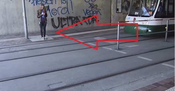 Flickan tittar på mobilen och märker inte spårvagnen. Men vad hon ser på marken, räddar hennes liv.